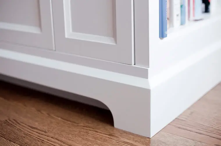 A close view of a painted cabinet end panel with a curved base detail