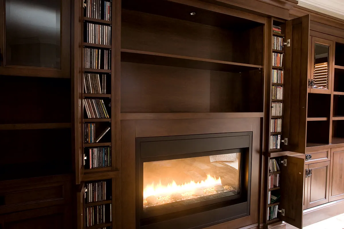 A cherry built-in wall with bookshelves either side of a fireplace